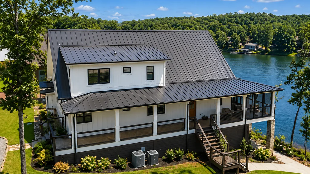 Elevated white lake house with a dark standing-seam metal roof and a covered porch overlooking the water.