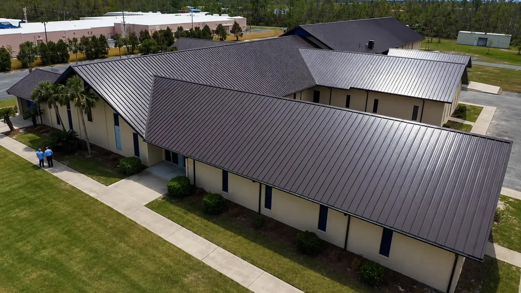 Aerial view of a commercial building with a dark standing-seam metal roof and several connected roof planes.