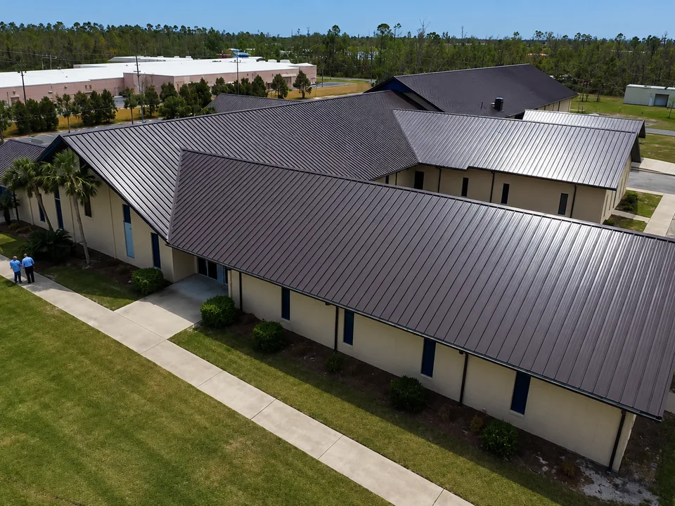 Aerial view of a low-rise commercial building with a wide bronze standing seam metal roof