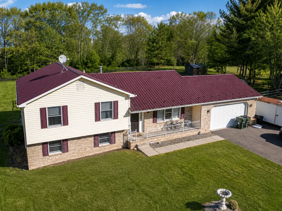 Aerial view of a single-storey home with a newly fitted deep red metal roof and attached garage